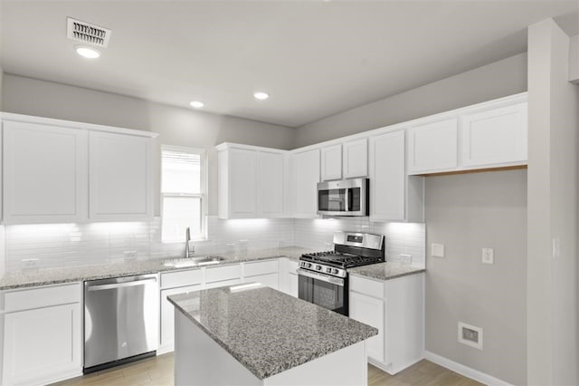 kitchen with appliances with stainless steel finishes, sink, a kitchen island, and white cabinets