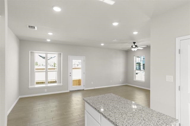 kitchen with a healthy amount of sunlight, light stone countertops, and white cabinets