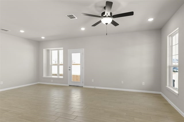 empty room featuring ceiling fan, plenty of natural light, and light wood-type flooring