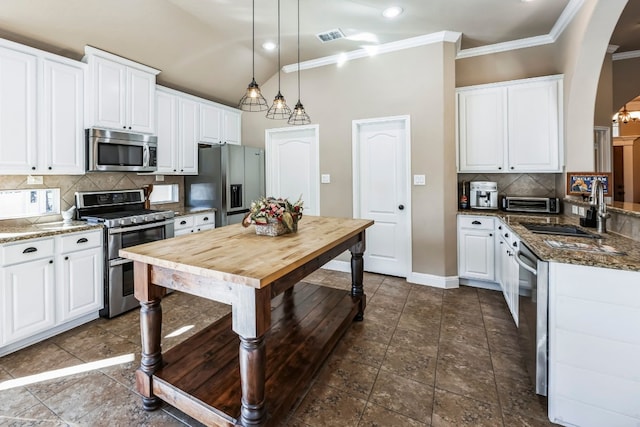 615 Mountain Crest Dr, Wimberley, TX 78676 - kitchen with appliances with stainless steel finishes, arched walkways, ornamental molding, white cabinetry, and tasteful backsplash