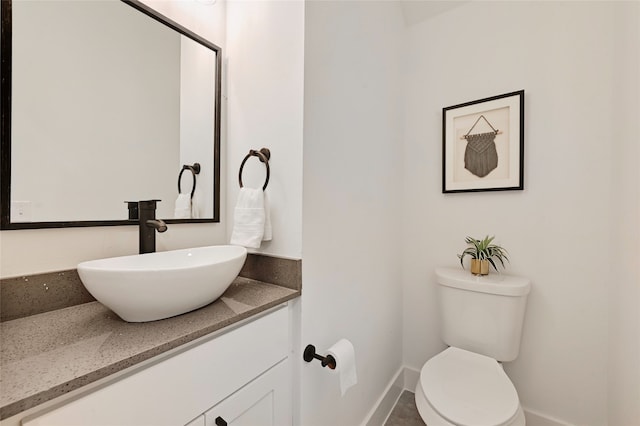 half bath featuring toilet, baseboards, and vanity