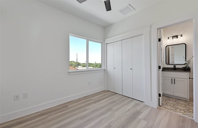 unfurnished bedroom featuring baseboards, visible vents, connected bathroom, light wood-style floors, and a closet