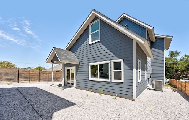 back of property with a fenced backyard and central AC unit