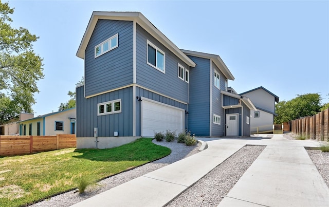 contemporary home featuring a garage, fence, board and batten siding, and a front yard