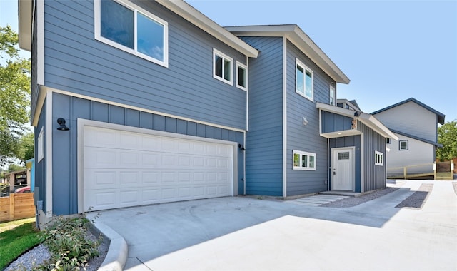 exterior space with a garage, fence, board and batten siding, and concrete driveway