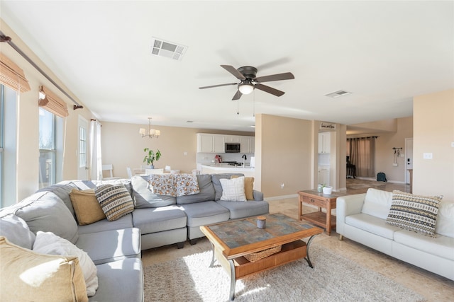 tiled living room featuring sink and ceiling fan with notable chandelier