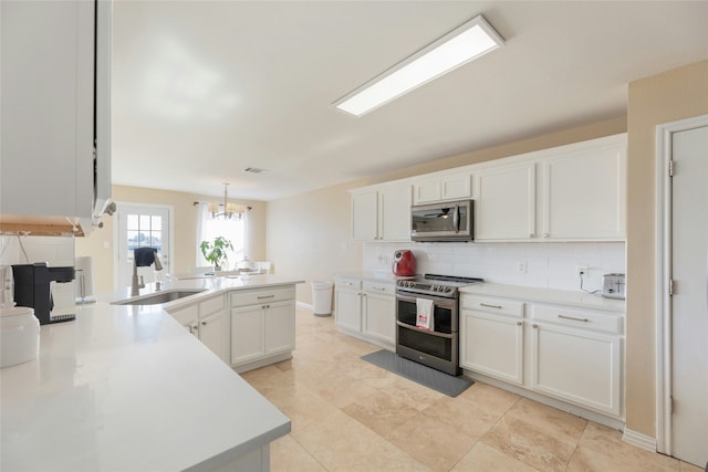 kitchen featuring appliances with stainless steel finishes, pendant lighting, sink, white cabinets, and decorative backsplash