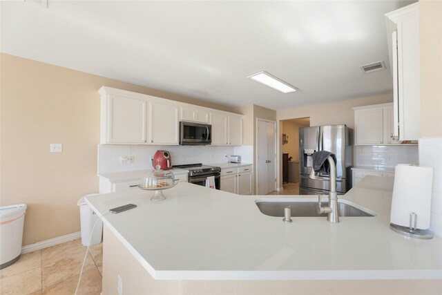 kitchen with tasteful backsplash, appliances with stainless steel finishes, sink, and white cabinets