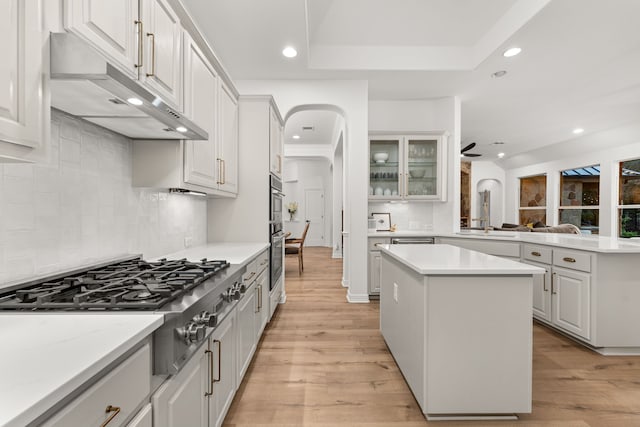 kitchen featuring white cabinetry, stainless steel appliances, a center island, tasteful backsplash, and light hardwood / wood-style floors