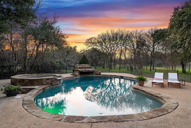 pool at dusk featuring an in ground hot tub and a patio