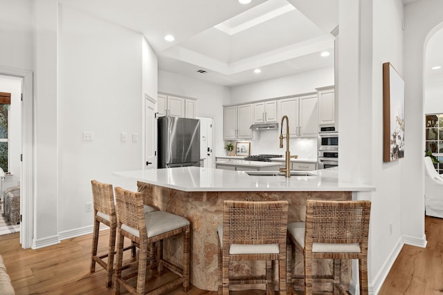 kitchen with a breakfast bar, backsplash, light hardwood / wood-style floors, kitchen peninsula, and stainless steel appliances