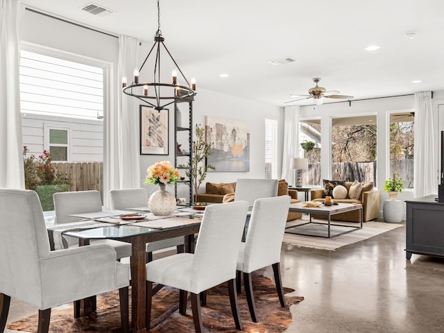 dining area featuring ceiling fan with notable chandelier and concrete floors