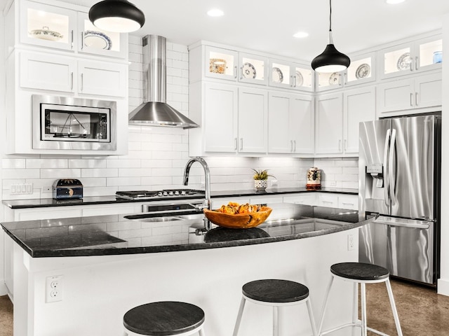 3711 Garden Villa Ln Unit A, Austin, TX 78704 - kitchen featuring stainless steel appliances, wall chimney range hood, a kitchen island with sink, white cabinetry, and decorative light fixtures