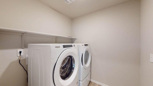 laundry area with washing machine and clothes dryer and light hardwood / wood-style floors