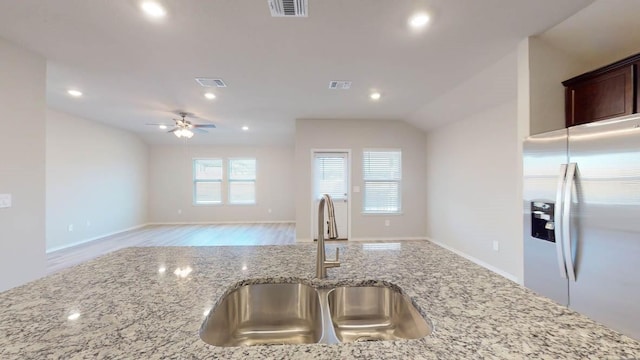 kitchen featuring stainless steel fridge with ice dispenser, lofted ceiling, sink, ceiling fan, and light stone counters