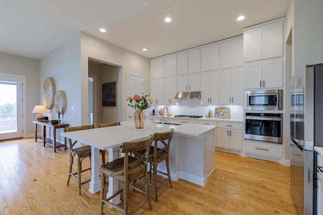 kitchen featuring white cabinetry, sink, backsplash, stainless steel appliances, and light wood-type flooring