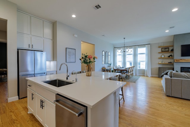 kitchen featuring white cabinetry, appliances with stainless steel finishes, sink, and a center island with sink