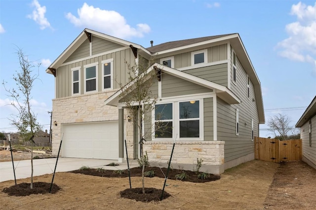 view of front of property with concrete driveway, stone siding, an attached garage, fence, and board and batten siding