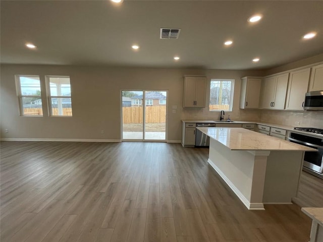 kitchen with tasteful backsplash, appliances with stainless steel finishes, a center island, and sink