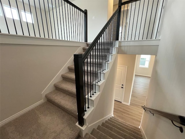 stairs with hardwood / wood-style floors and a high ceiling