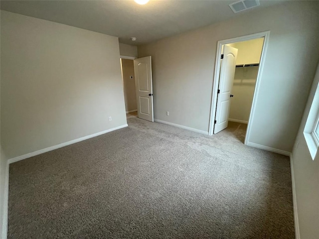 unfurnished bedroom with a walk in closet, light colored carpet, and a closet