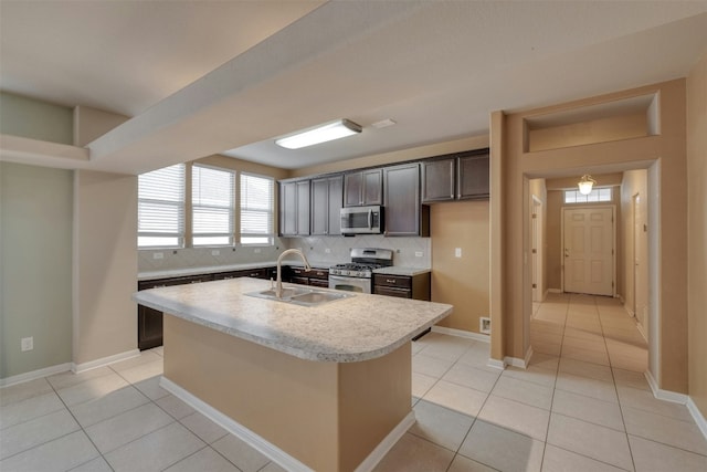 kitchen featuring appliances with stainless steel finishes, sink, a center island with sink, and light tile patterned floors