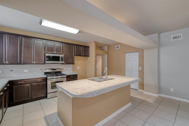 kitchen featuring sink, light tile patterned floors, an island with sink, stainless steel appliances, and decorative backsplash