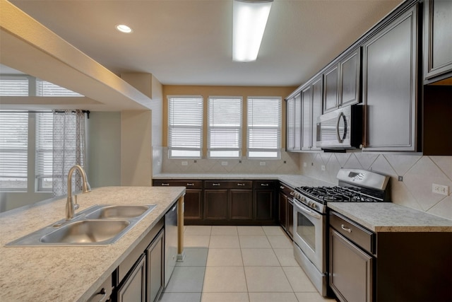 kitchen with sink, decorative backsplash, light tile patterned floors, and appliances with stainless steel finishes