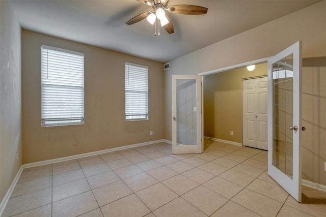 unfurnished bedroom featuring light tile patterned floors, a closet, french doors, and ceiling fan