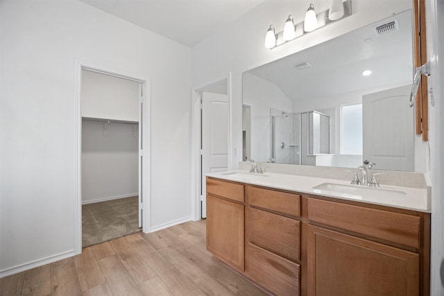 bathroom with vanity, a shower with shower door, and wood-type flooring