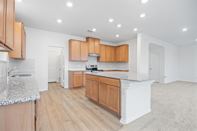 kitchen featuring electric stove, sink, backsplash, a center island, and light stone counters