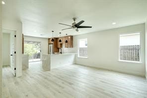 unfurnished living room with ceiling fan, a healthy amount of sunlight, and light hardwood / wood-style floors