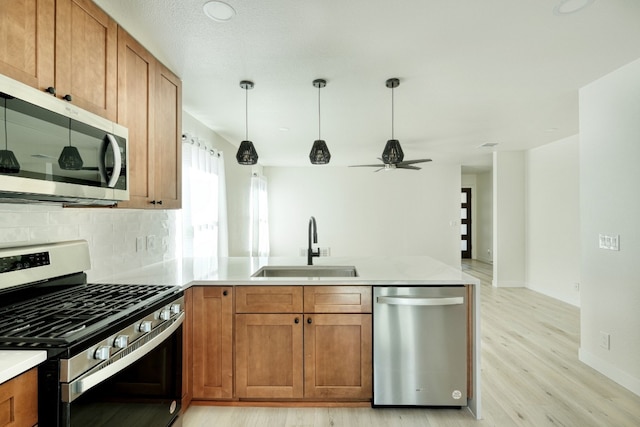 kitchen featuring sink, appliances with stainless steel finishes, light hardwood / wood-style floors, decorative backsplash, and kitchen peninsula