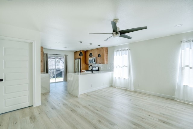 kitchen featuring sink, appliances with stainless steel finishes, kitchen peninsula, light hardwood / wood-style floors, and decorative backsplash