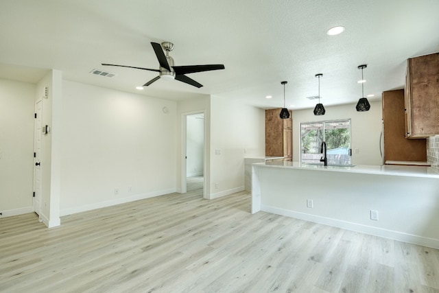 unfurnished living room with ceiling fan, sink, and light hardwood / wood-style flooring