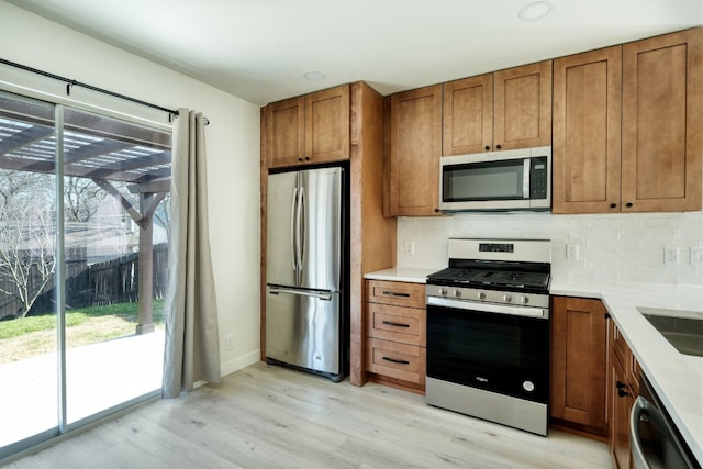 kitchen featuring stainless steel appliances, backsplash, and light hardwood / wood-style floors