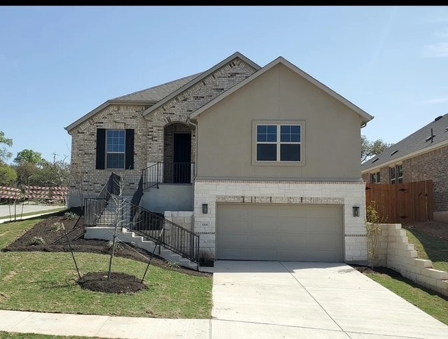 view of front of property featuring a front lawn, a garage, brick siding, concrete driveway, and fence