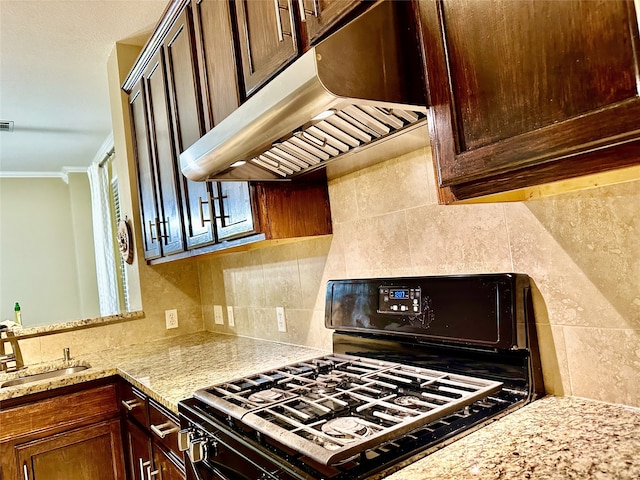 kitchen with sink, crown molding, black gas range, backsplash, and light stone countertops