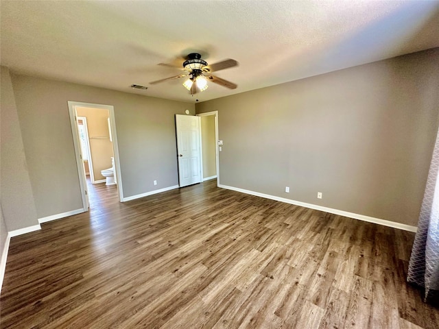 unfurnished bedroom with ceiling fan, wood-type flooring, ensuite bathroom, and a textured ceiling