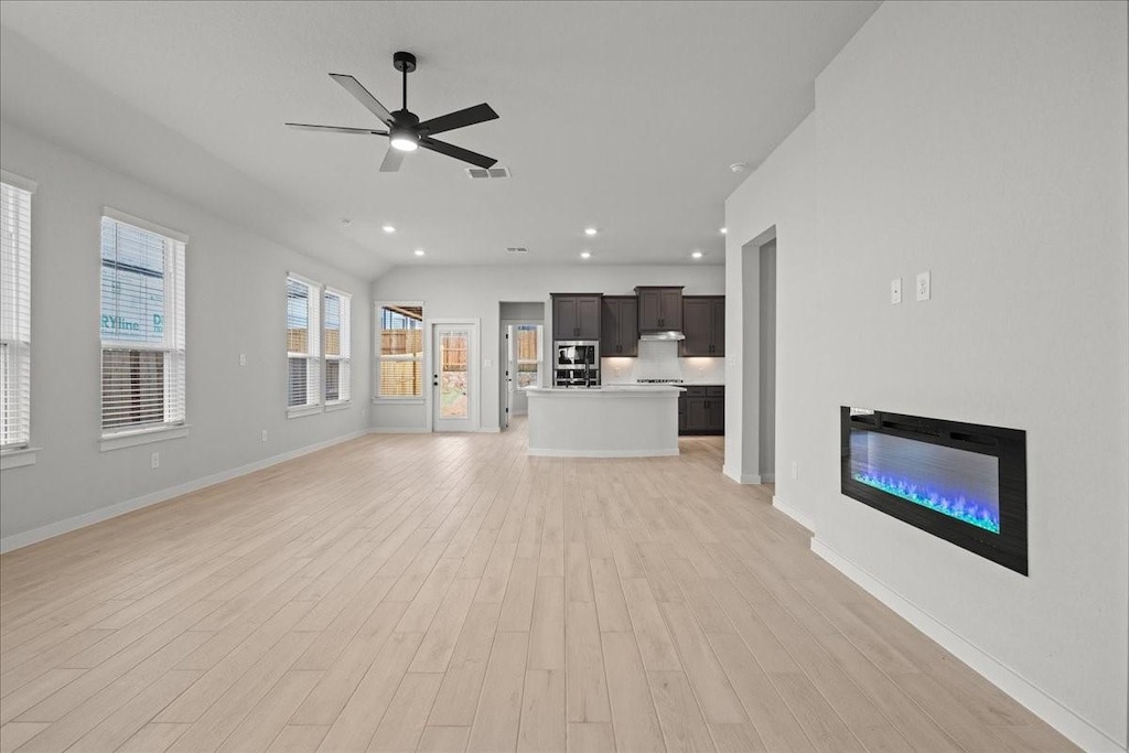 unfurnished living room with vaulted ceiling, ceiling fan, and light hardwood / wood-style flooring