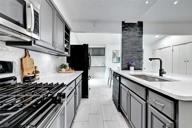 kitchen with a sink, marble finish floor, light countertops, decorative backsplash, and black appliances