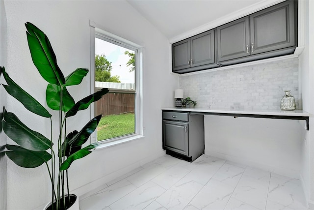 kitchen with marble finish floor, gray cabinets, light countertops, backsplash, and vaulted ceiling