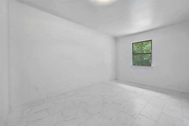 spare room with marble finish floor and baseboards