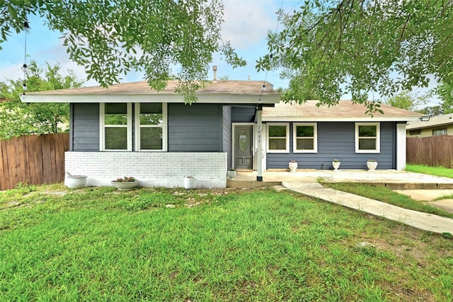 view of front of property with brick siding, fence, and a front yard