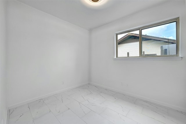 empty room featuring marble finish floor and baseboards