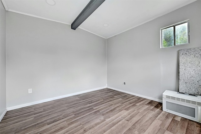 unfurnished living room featuring lofted ceiling with beams, wood finished floors, baseboards, heating unit, and crown molding