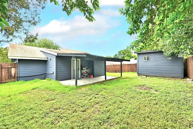 back of house with a fenced backyard, an outdoor structure, a lawn, a storage unit, and a patio area