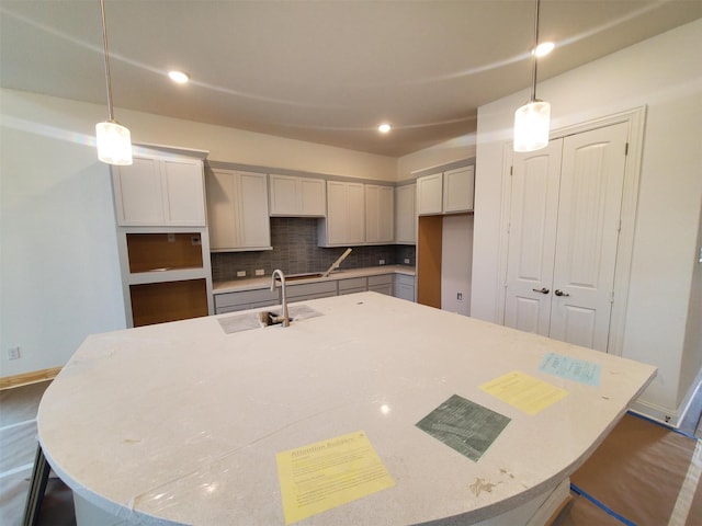 kitchen with hanging light fixtures, sink, and an island with sink