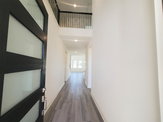 hallway featuring a high ceiling, baseboards, and wood finished floors