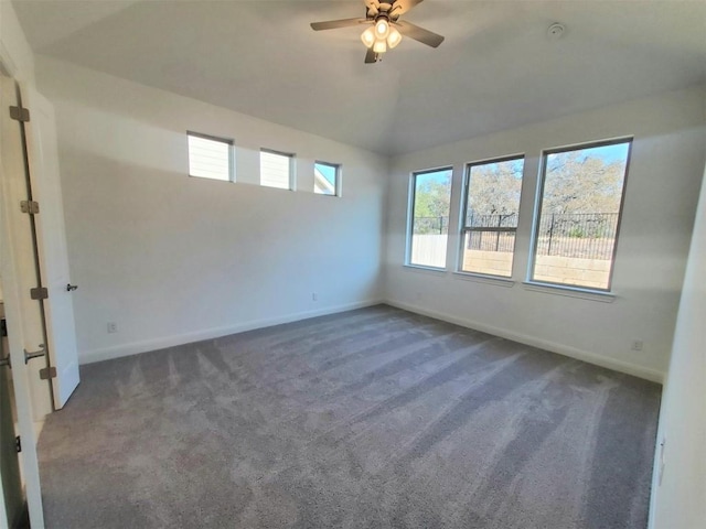 unfurnished room with lofted ceiling, dark colored carpet, ceiling fan, and baseboards